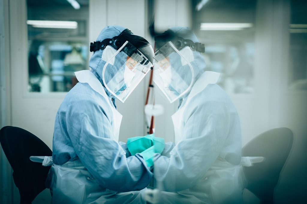 Person working while wearing protective gear, their silhouette reflected in glass