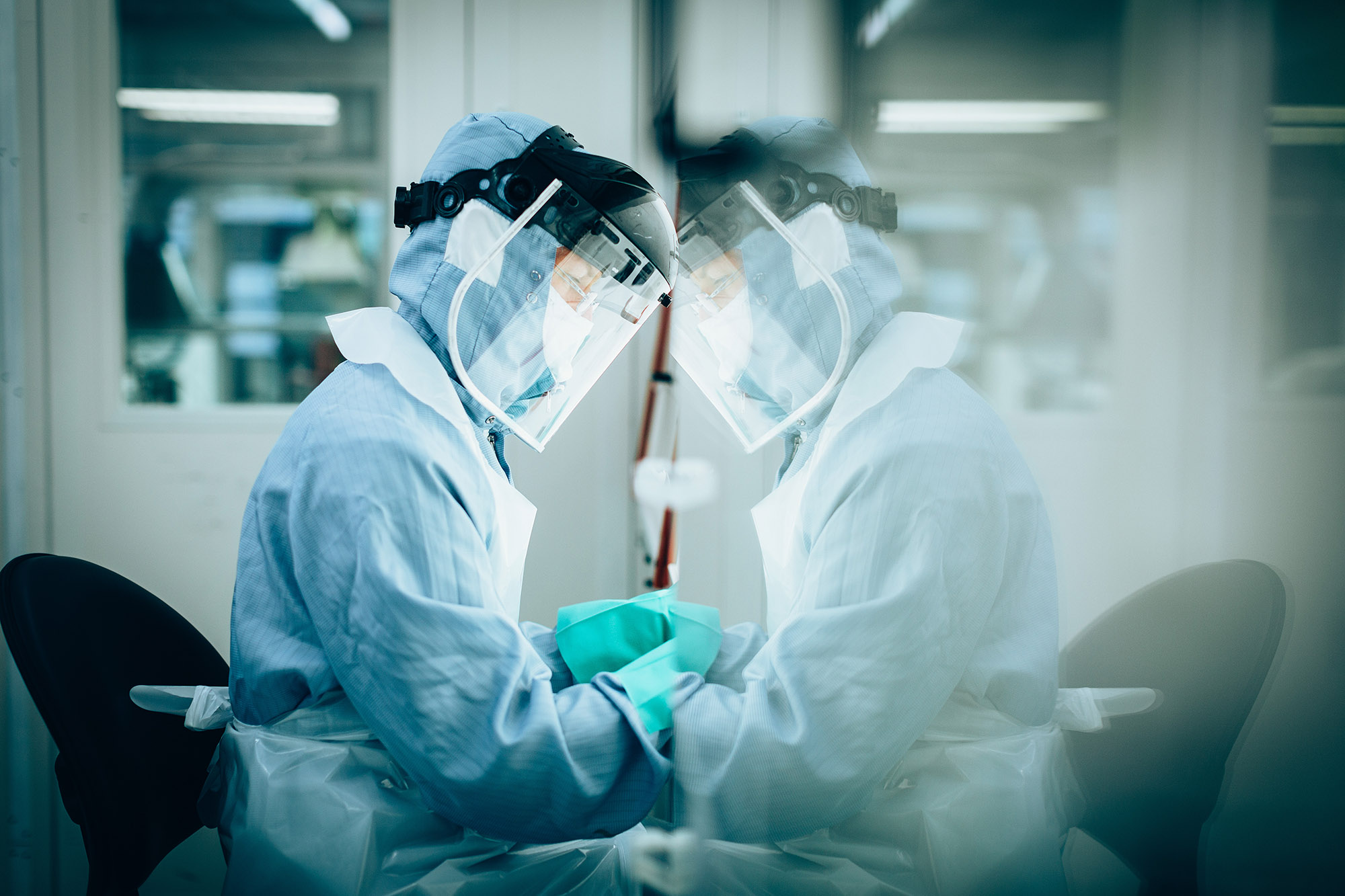 Person working while wearing protective gear, their silhouette reflected in glass