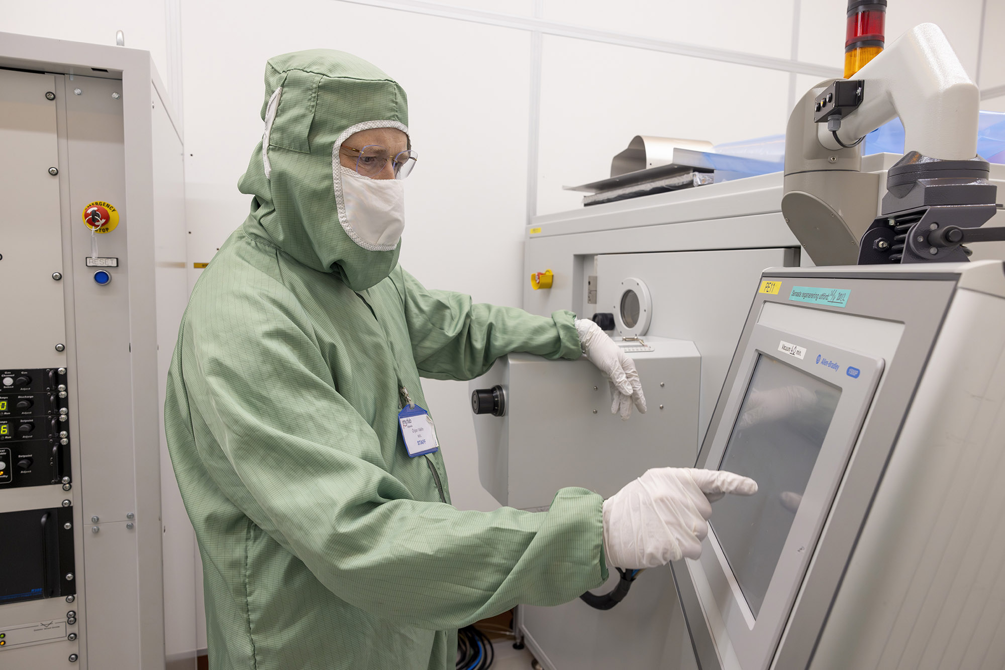 Person wearing protective gear interacting with a screen of a big machine
